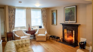A cozy living room with a fireplace, two armchairs, a sofa, and a dining table. - Cottage 360 - Clifden - sleeps 6 guests  in 3 bedrooms (Clifden)