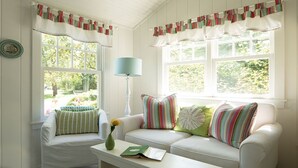 A cozy room with a white sofa, striped pillows, and a vase with flowers. - SWEET DREAMS COTTAGE (Kennebunkport)
