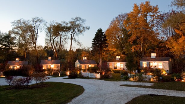 A residential area with multiple houses, a gravel driveway, and a white picket fence. - SWEET DREAMS COTTAGE (Kennebunkport)