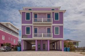 A multi-story building with a purple facade, a balcony on the second floor, and a visible entrance with a door and windows.