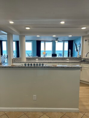 A spacious kitchen with a large island, a view of the ocean, and a balcony with outdoor seating. - OCEANFRONT 3BD-3B Condo - ground floor. (Daytona Beach)