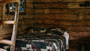 Een rustiek houten interieur met een bed, een ladder en een gewatteerde deken.