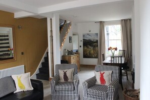 Relax in this inviting living area with a sofa, armchairs, and dining table near a large window.