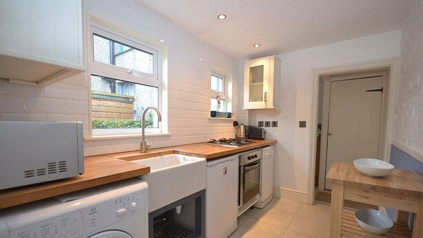 A compact kitchen with a washing machine, a stove, and a sink.