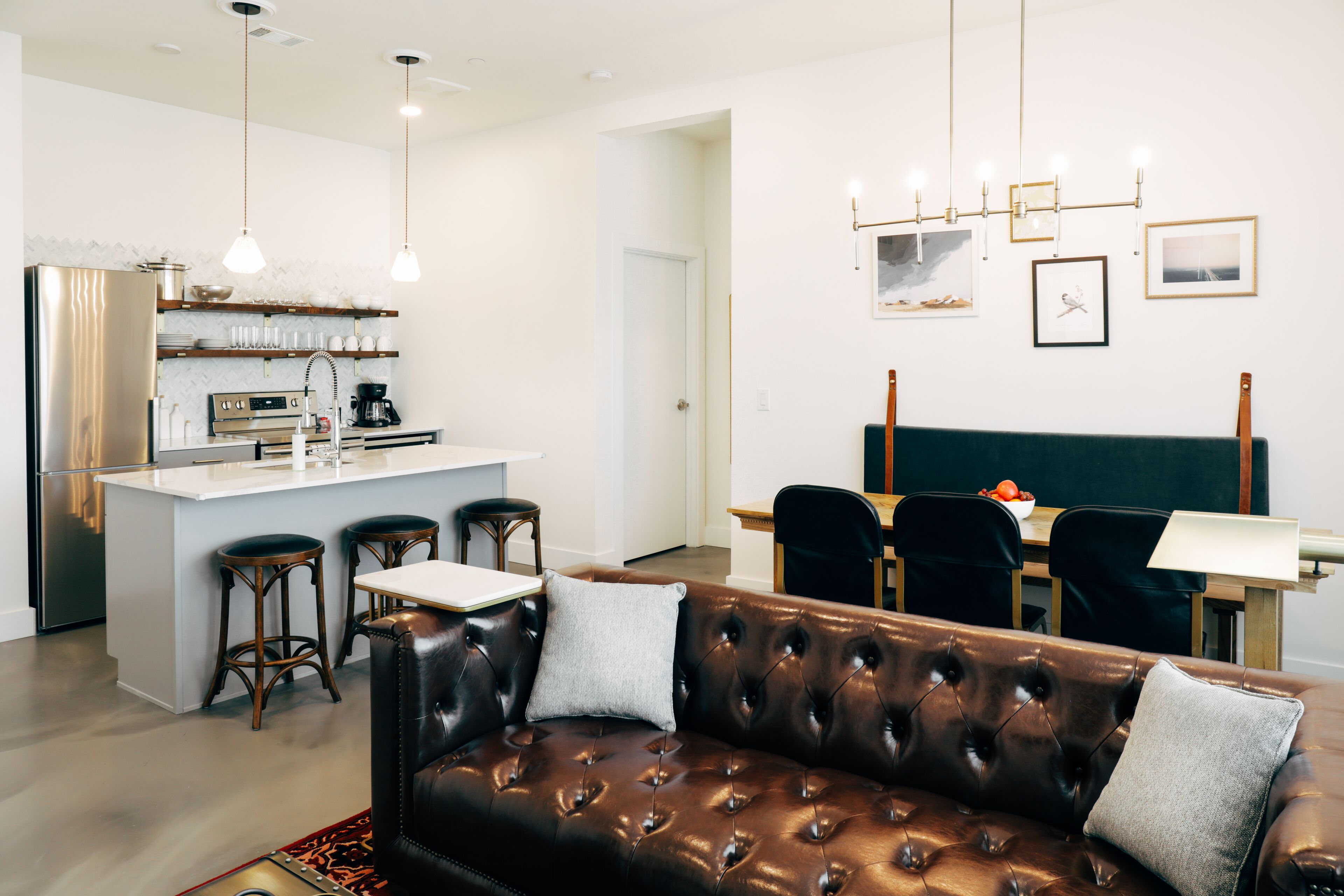 Una cocina moderna con una isla central, taburetes de bar e iluminación colgante.