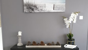 A modern living room with a grey wall, a black console table, and a framed landscape painting.