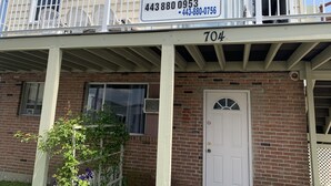 A two-story building with a balcony, a sign advertising apartments for rent, and a door with a number '704' above it. - Elis Apartments Unit 6 (Ocean City)
