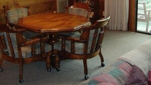 A wooden dining room with a large table and chairs, a chandelier, and a bookshelf. - Spacious Mountain Cabin in Gated Community (Triplett)