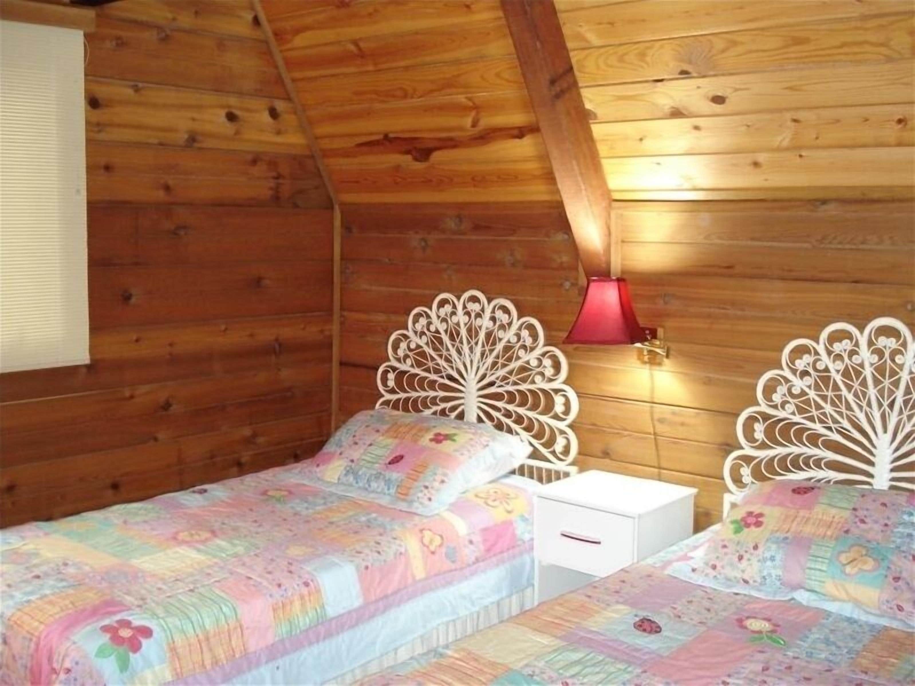 Ein gemütliches Blockhausschlafzimmer mit zwei Einzelbetten, Holzwänden und einer schrägen Decke.