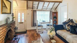 Ein gemütliches Wohnzimmer mit Kamin, eine Essecke mit Tisch und Stühlen sowie eine Couch mit Kissen.