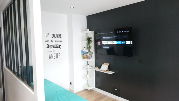 A modern room with a bed, a wall-mounted TV, and a motivational quote.