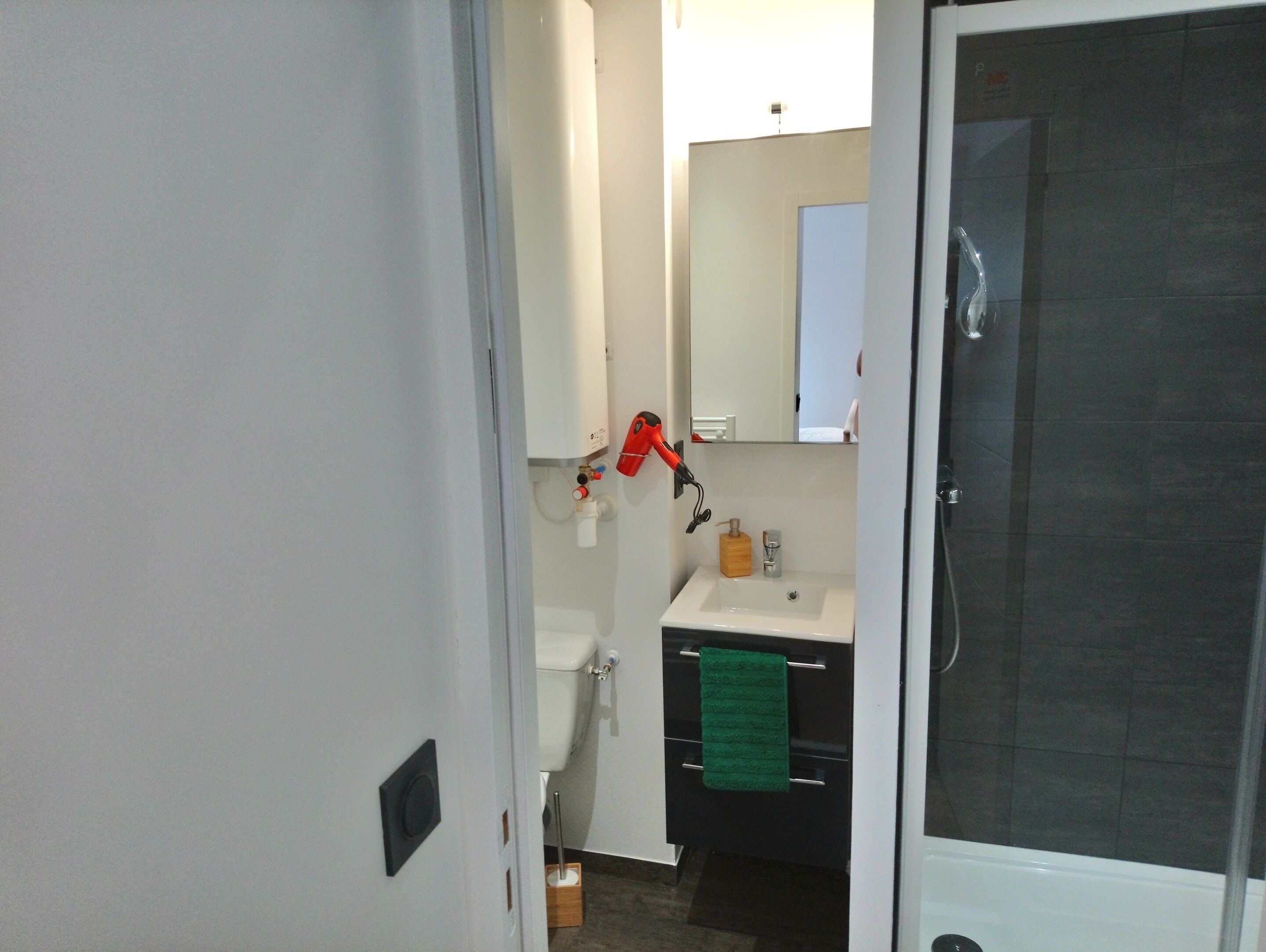 A bathroom with a toilet, sink, mirror, and shower.