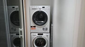 Een wasserette met twee gestapelde wasmachines en een droger.
