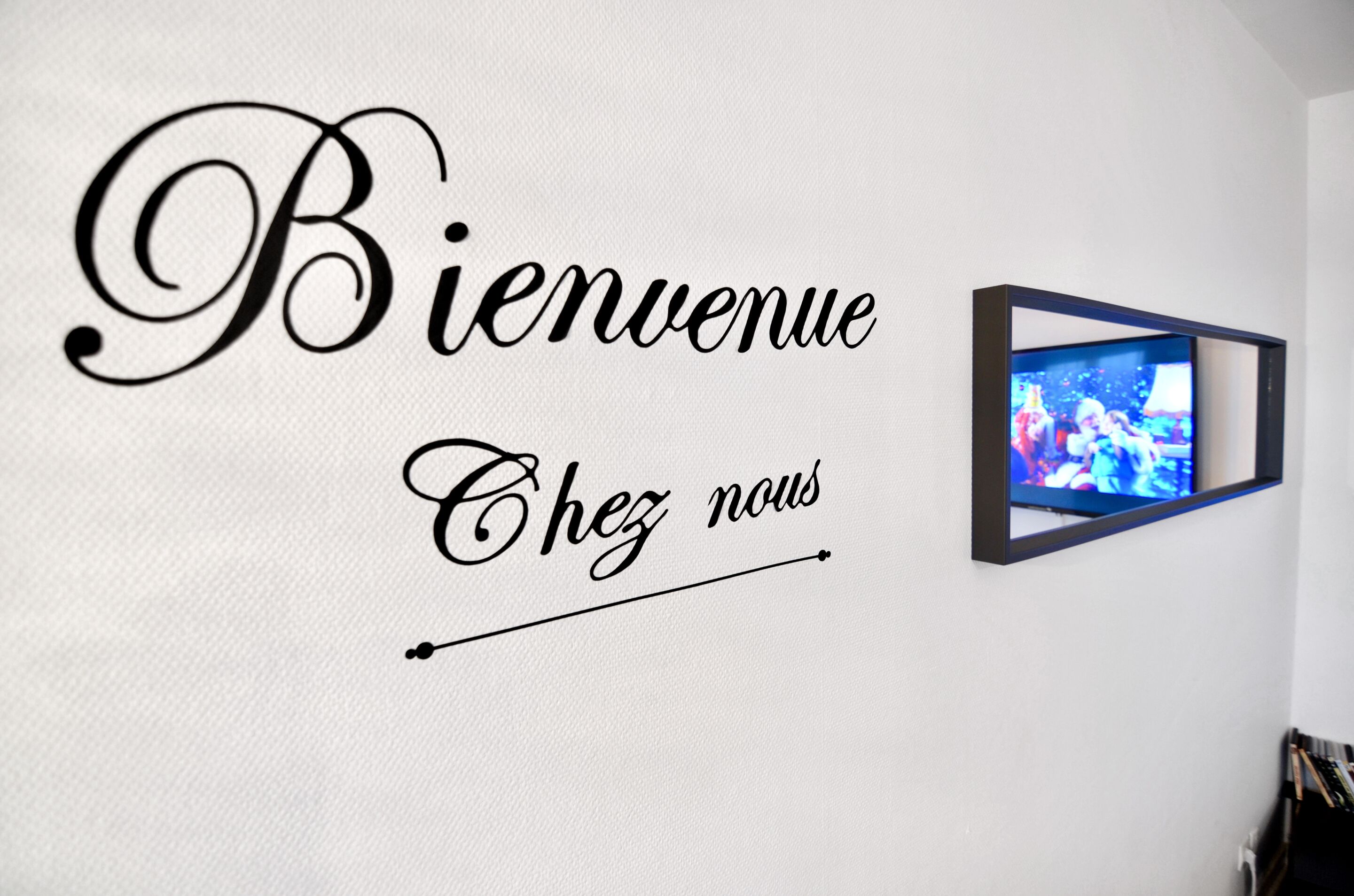 A wall with a welcome sign and a framed picture.