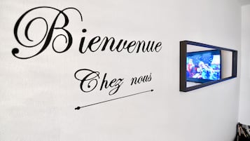 A wall with a welcome sign and a framed picture.
