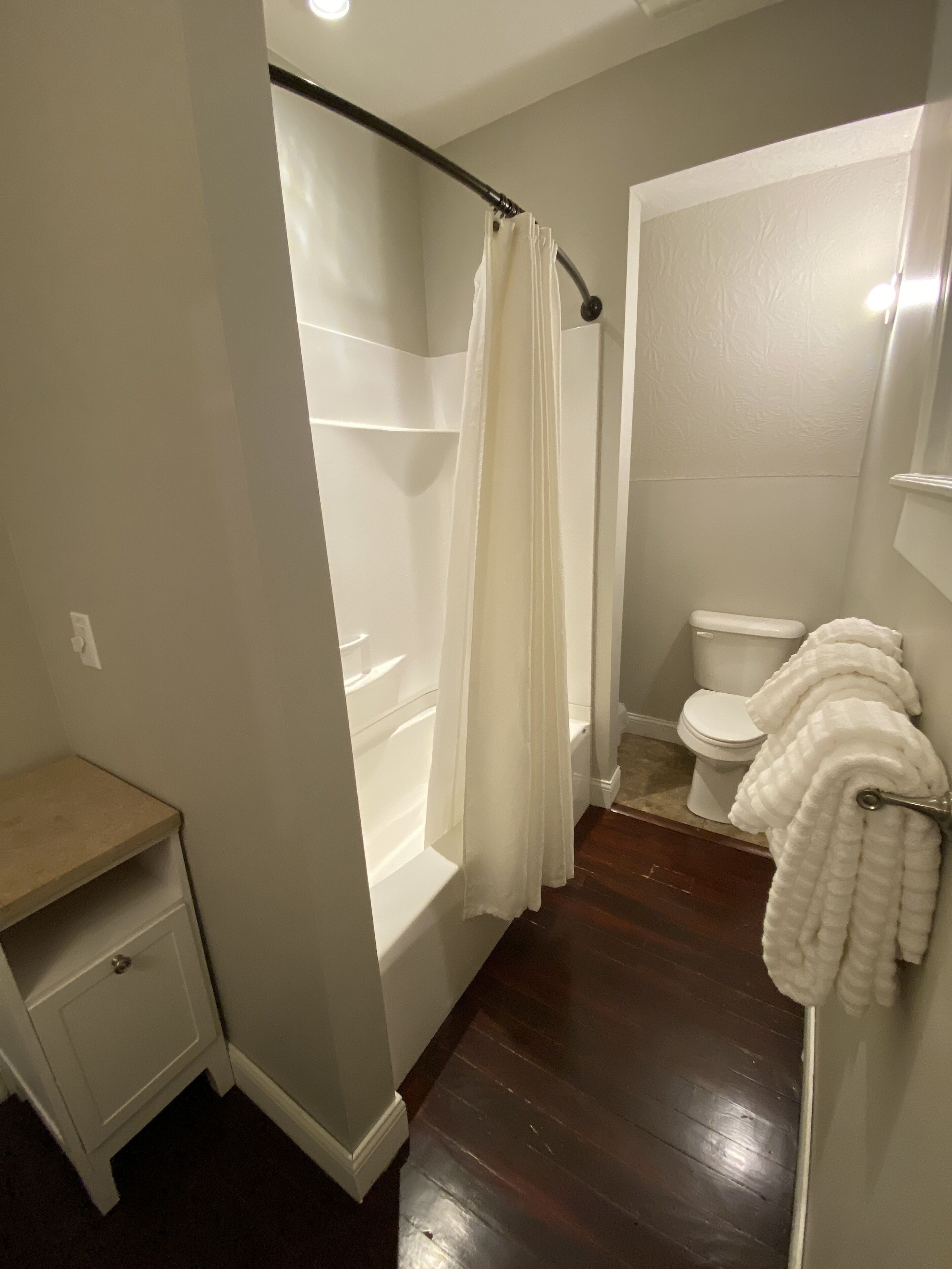 Un baño con bañera, inodoro y un pequeño tocador con espejo.