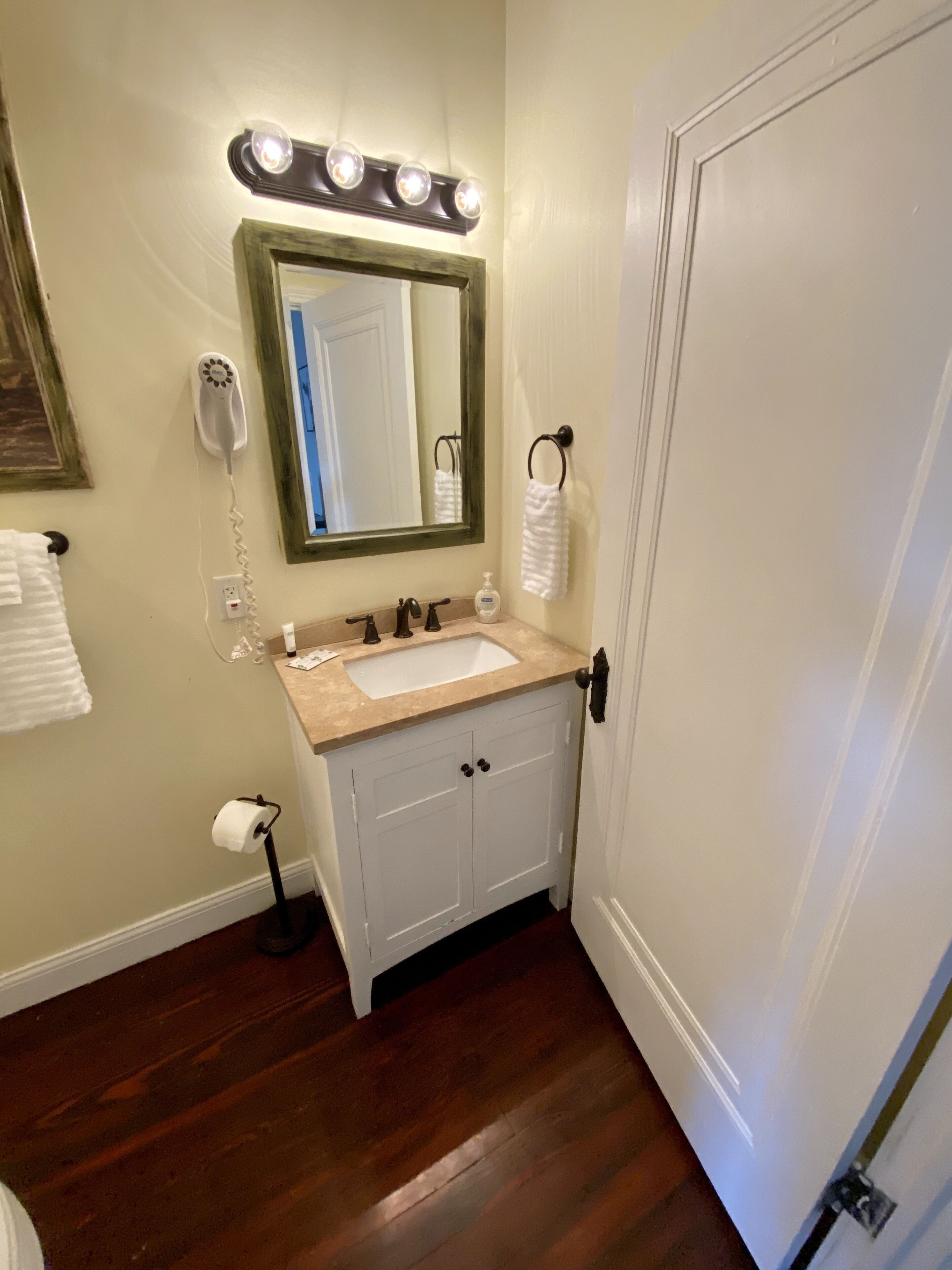A bathroom with a vanity, sink, mirror, and a telephone.