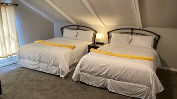 A hotel room with two beds, a nightstand with a lamp, and a window with curtains.