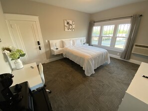 A bedroom with a bed, bedside table, nightstand, and a window with curtains. - Twin Lakes Creamery, Grill & Inn (Leitchfield)