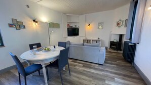 Un salon moderne avec un coin repas, un canapé gris et un téléviseur.