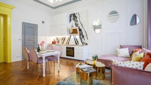 A modern living room with a dining area, a kitchen, and a seating area with a sofa and cushions. - President - romantic design apartment in the centre of Prague (Hlavní město Praha)