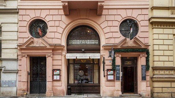 A building facade with a central entrance, two circular windows, and a sign for a post office. - President - romantic design apartment in the centre of Prague (Hlavní město Praha)