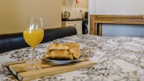 A bed with a floral bedspread, a plate of croissants, and a glass of orange juice on a wooden tray.