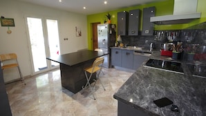 Uma cozinha moderna com uma ilha grande, armários cinza e uma parede verde decorativa.