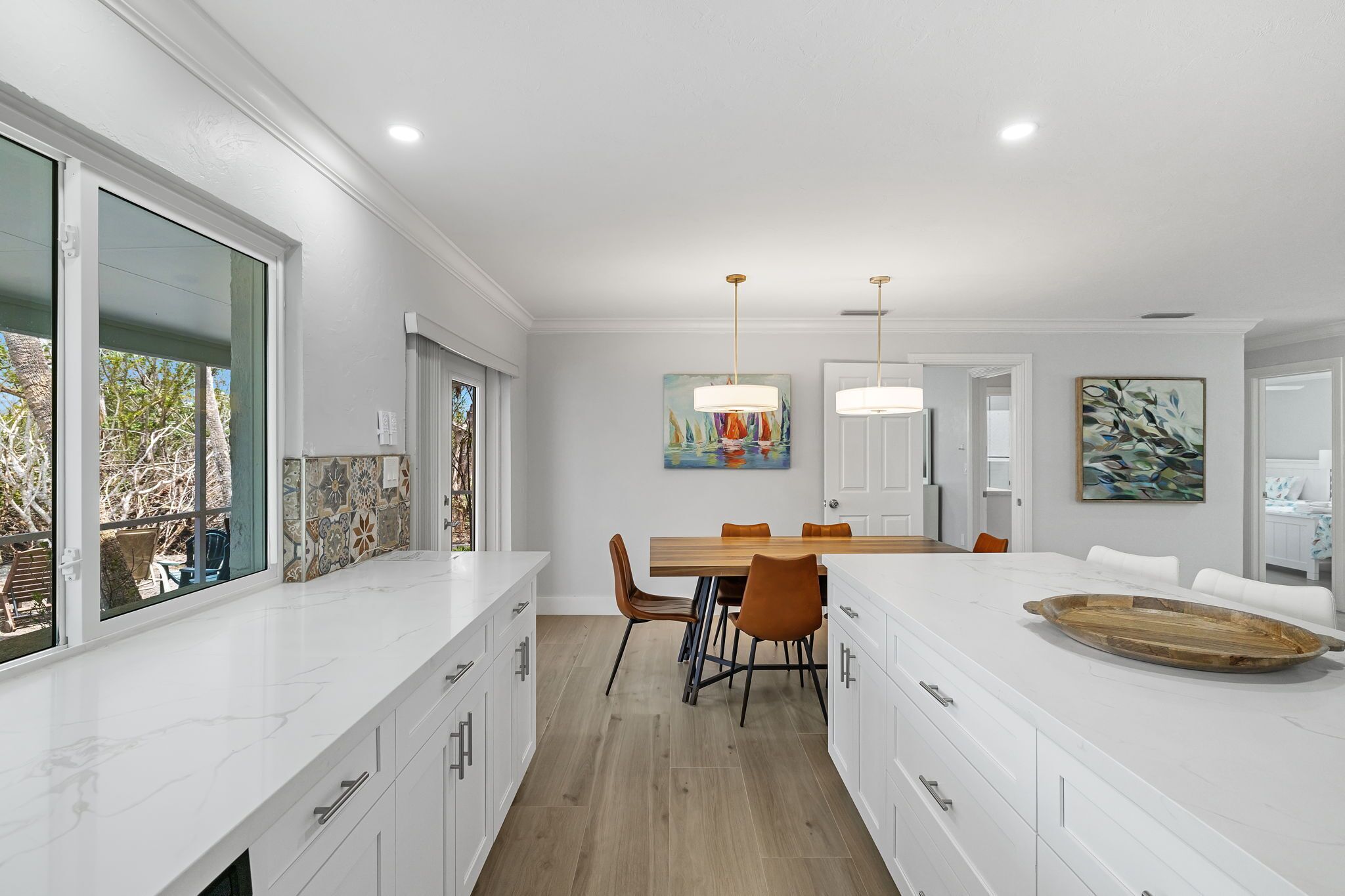 A modern kitchen with white cabinetry, a wooden dining table, and a large island.