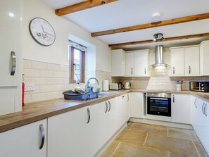 A kitchen with white cabinets, a built-in oven, a sink with a dish rack, and a clock on the wall. - 2 bedroom accommodation in Clay Cross (Clay Cross)