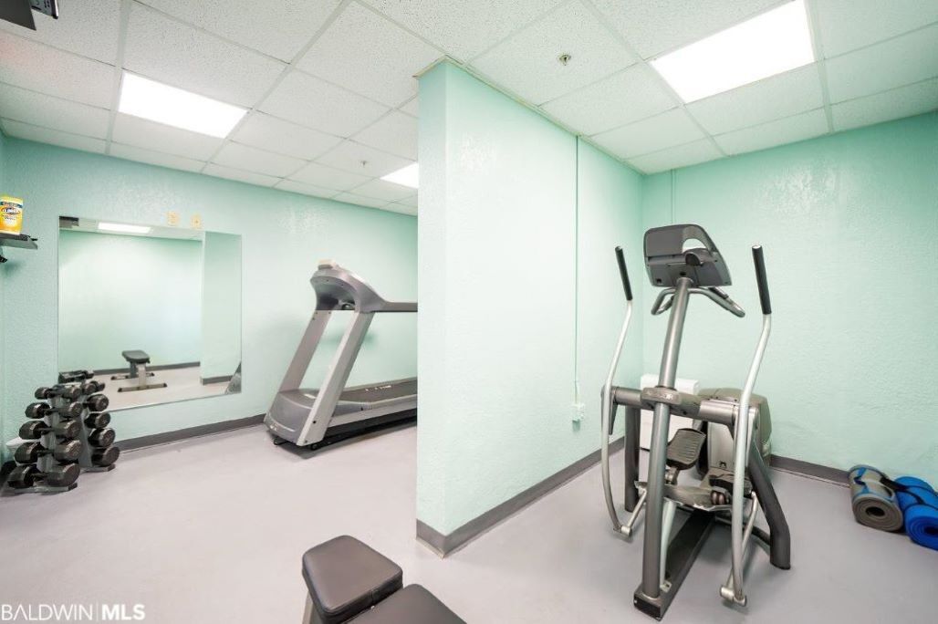 A gym with a treadmill, elliptical, and free weights.
