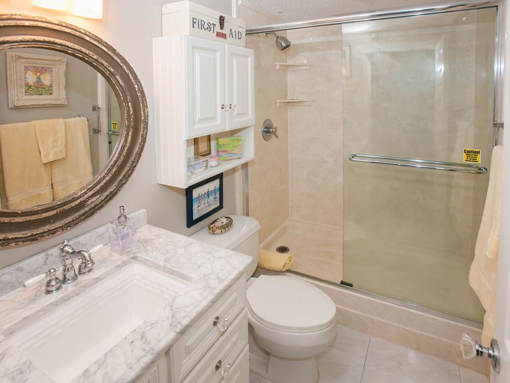 A bathroom with a marble sink, a toilet, a glass shower enclosure, and a cabinet labeled "First Aid".