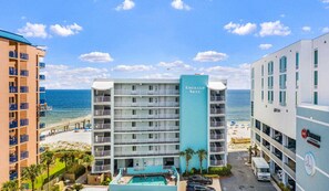 Un hôtel à plusieurs étages doté d’une piscine, offrant une vue sur la plage et comprenant plusieurs balcons.