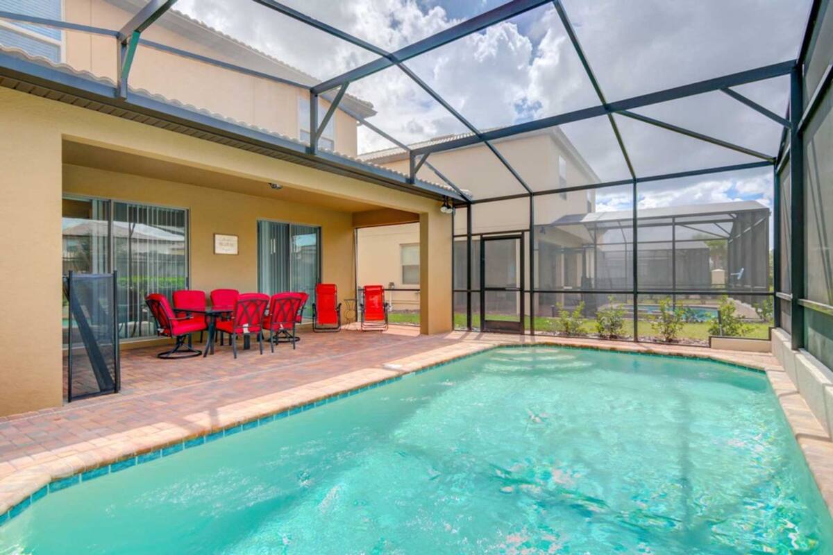 Une piscine intérieure dotée d’une paroi vitrée, de chaises rouges et d’un espace patio.
