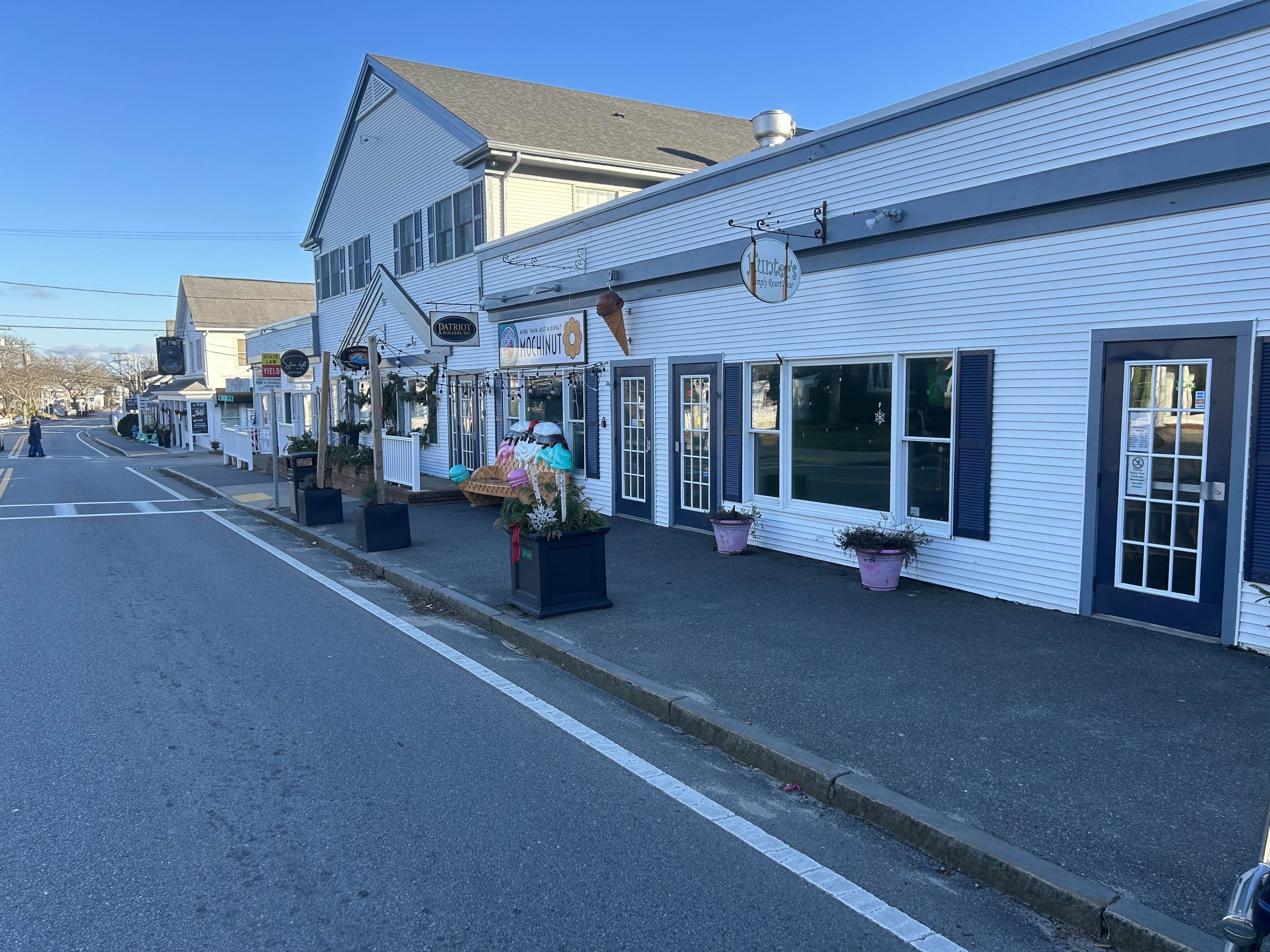 Une rangée de bâtiments blancs avec des devantures de magasins, dont un restaurant et un bar.