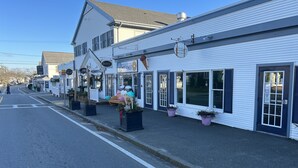 A row of white buildings with storefronts, including a restaurant and a bar. - Cozy condo in downtown Harwich Port short walk to Bank Street Beach (Harwich)