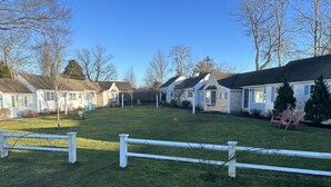 A row of single-story houses with a white picket fence in the foreground. - Cozy condo in downtown Harwich Port short walk to Bank Street Beach (Harwich)