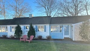 A single-story house with a front porch, two potted evergreen trees, and two pink Adirondack chairs. - Cozy condo in downtown Harwich Port short walk to Bank Street Beach (Harwich)