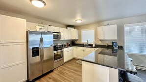 A modern kitchen with white cabinets, stainless steel appliances, and a wooden floor. - Edgewater #4 Moose (Polson)