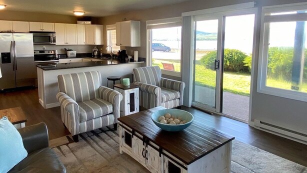 A modern living room with a sofa, a coffee table, and a kitchen in the background. - Edgewater #4 Moose (Polson)