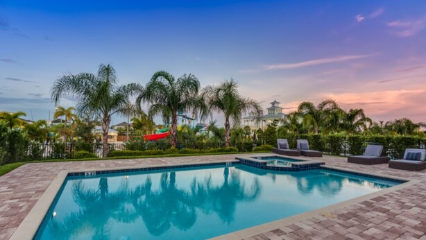A rectangular swimming pool with a tiled edge, surrounded by lounge chairs and palm trees. - Encore Club at Reunion by Florida Star Vacations (Kissimmee)