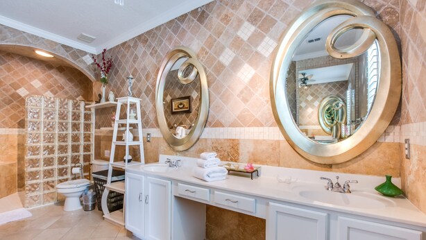 A bathroom with a large vanity, a toilet, and a shower area. - Highlands Reserve by Florida Star Vacations (Davenport)