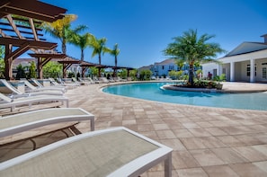 A pool area with lounge chairs and a pergola, surrounded by palm trees and a clear blue sky. - West Lucaya Village Resort by Florida Star Vacations (Kissimmee)