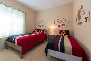 A bedroom with two beds, a nightstand, a lamp, and Mickey Mouse-themed wall decals. - Vista Cay Resort by Florida Star Vacations (Orlando)