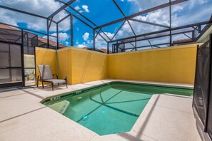 A swimming pool with a glass ceiling, a chair, and a yellow wall.