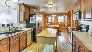 A kitchen with wooden cabinets, a central island, stainless steel appliances, and pendant lighting. - Scenic Views & Game Room: Garden City Retreat! (Garden City)