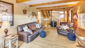 A log cabin interior with two leather sofas, a wooden table, and a fireplace. - Scenic Views & Game Room: Garden City Retreat! (Garden City)