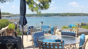Une terrasse dotée de mobilier d’extérieur, offrant une vue sur un lac et sur une côte lointaine.