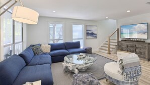 A modern living room with a sectional sofa, a glass coffee table, and a fireplace.