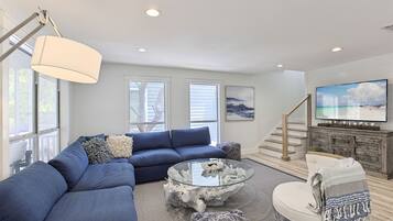 A modern living room with a sectional sofa, a glass coffee table, and a fireplace.